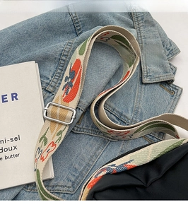 Close-up of adjustable woven canvas shoulder strap with colorful floral patterns