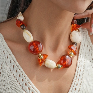 Gros plan d'un modèle portant un collier de pull géométrique en perles acryliques ambre et crème