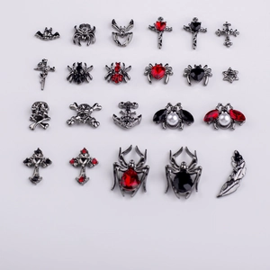 Flat lay of gothic gunmetal nail art charms including skulls, spiders and crosses