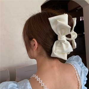 Close-up of a large white satin bow hair claw clip styled on a woman's hair
