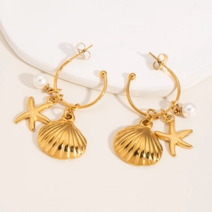 Close-up of gold hoop earrings with shell, starfish pendants and pearls