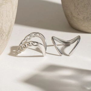 Detail of silver chain weave and V-shaped minimalist adjustable open rings on stone texture