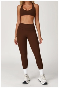 Detail of high-waist yoga leggings and sports bra in dark brown with stretch fabric