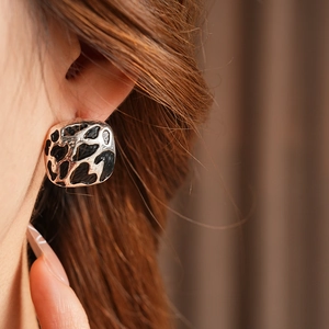 Détail de la boucle d'oreille carrée argentée à motif léopard sur l'oreille du mannequin