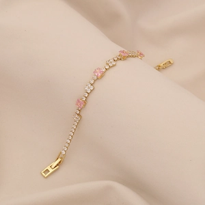 Close-up of gold chain bracelet with pink square crystal and white zircon accents