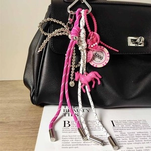Dettaglio portachiavi intrecciato rosa con ciondolo a pony su borsa di pelle nera