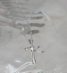 Macro shot of silver lava textured cross pendant with liquid metal finish and chain