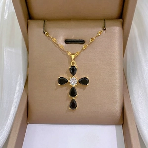 Elegant gold cross pendant necklace with black teardrop crystals on white silk