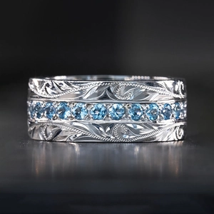 Gepolijste brede ring met blauwe edelstenen en gegraveerde bladpatroon details