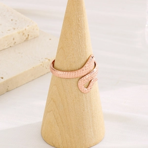 Macro detail of rose gold snake-textured ring on a wooden cone display stand