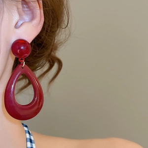 Close-up of model wearing retro burgundy resin teardrop earrings with silver needle