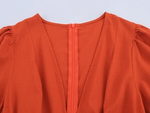 Detail view of orange V-neck dress with front zipper and pleated shoulder seams