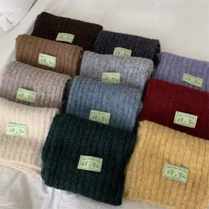 Macro shot of colorful thick knitted scarves neatly folded on white fabric