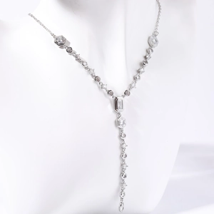 Dettaglio di una collana a Y d'argento con maglie in zircone su un busto bianco