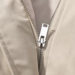 Macro shot of high-quality metal zipper detail on khaki motorcycle style windbreaker jacket