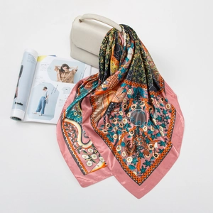 Detailed pattern of a 90cm square silk scarf with floral prints draped over a beige handbag