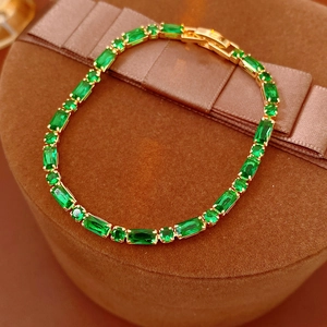 Detailed macro of green zircon tennis bracelet on velvet display with gold plating finish