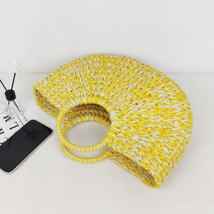 Handmade woven straw beach bag in yellow and cream with circular handles for summer vacations