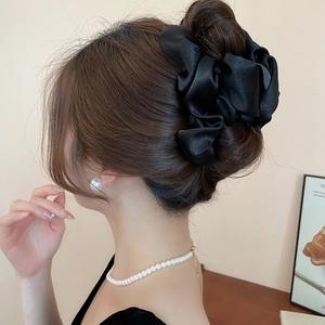 Detail view of a large black satin pleated claw clip on a French-style bun hairstyle