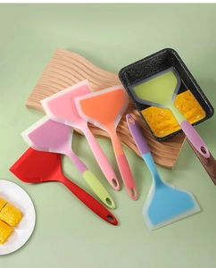 Détail d'une spatule large en silicone retournant des omelettes japonaises