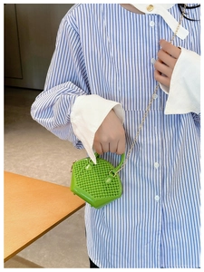 Detailed view of the green woven mini shell bag with elegant gold chain strap