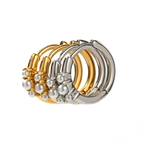 Fashionable gold and silver hoop earrings with three pearls on minimalist background