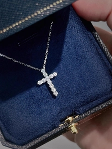 Close-up of sparkling zircon cross pendant in a premium deep blue jewelry gift box