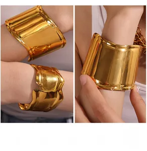 Detail view of bold gold irregular textured and smooth mirror wide bangle bracelets