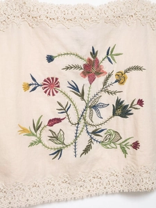 Detailed view of colorful floral embroidery and delicate lace edges on cotton linen fabric