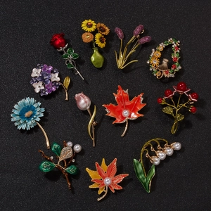 Vintage floral brooch set featuring enamel roses and sunflowers with pearls on black background