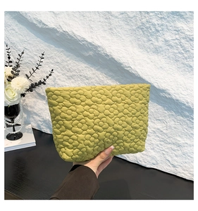 Close-up of grass green quilted makeup bag with 3D floral texture and soft nylon fabric