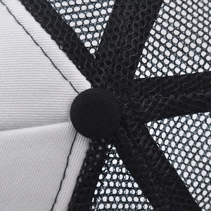 Close-up of breathable black mesh and white twill fabric stitching on a trucker hat