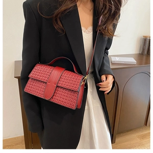 Detail shot of the red woven texture and elegant shoulder strap on the chic square handbag