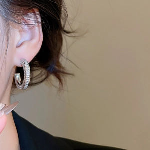 Detailed view of silver C-shaped earrings with shimmering cubic zirconia on female model
