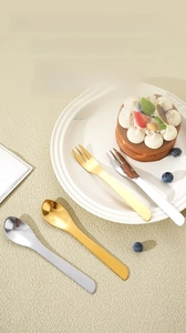 Detailed close-up of mirror-polished gold and silver dessert forks and spoons on light background