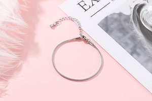 Detail of silver snake chain bracelet with adjustable extender on soft pink background