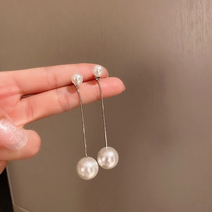 Détail de longues boucles d'oreilles perles avec chaîne serpent et design double perle