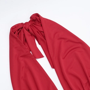 Detail of red halter neck dress showing elegant tie-back straps and premium knit fabric