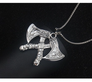 Detailed close-up of a silver Viking axe pendant with intricate Nordic rune textures