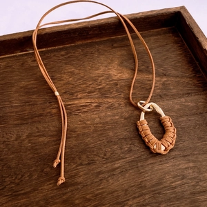 Détail d'un pendentif goutte vintage sur cordon en daim marron avec enroulement doré