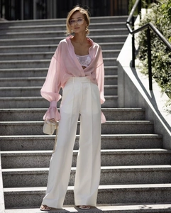 Detail of pink sheer long-sleeved shirt with lace bra and white wide-leg trousers