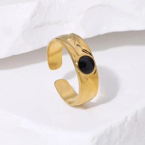 Close-up of golden adjustable ring with black enamel center on white marble