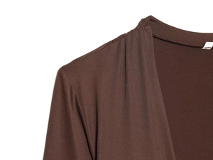 Macro detail of dark brown nylon fabric featuring elegant shoulder pleats and glossy texture