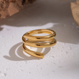 Macro shot of minimalist gold spiral ring with polished finish on white stone texture