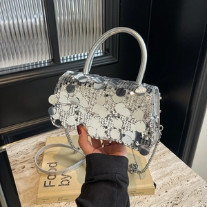 Detail of silver sequin handbag featuring a metallic chain strap and reflective texture