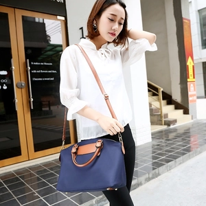 Large navy nylon tote bag with brown leather handles and a versatile crossbody strap