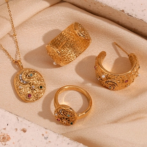 Detail of 18K gold plated jewelry set with hammered texture and celestial patterns
