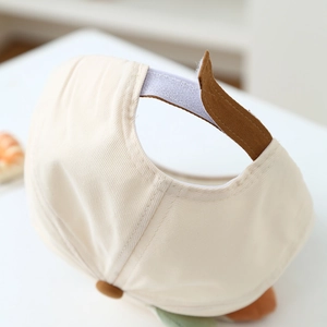 Detail of baby baseball cap with adjustable brown Velcro strap on cream cotton fabric