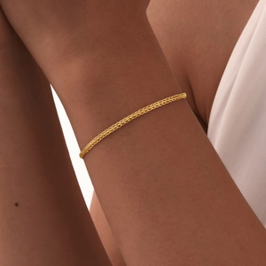 Detail of a minimalist 18K gold braided stainless steel chain necklace on a female model