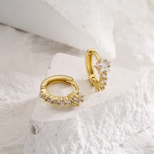 Gold plated copper huggie hoop earrings with clear cubic zirconia on stone background